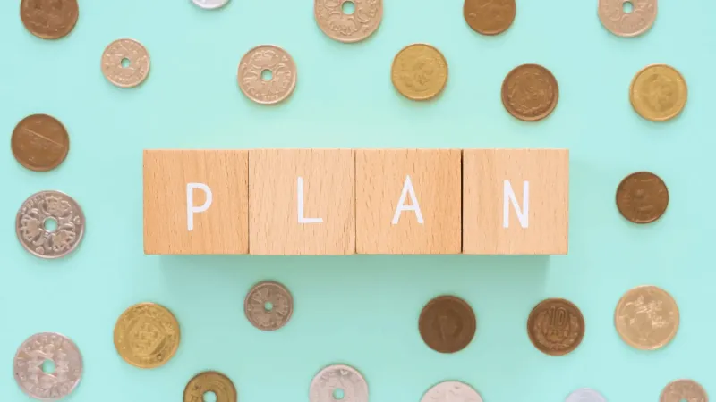 「PLAN」と書かれた木のオブジェとさまざまの国の小銭